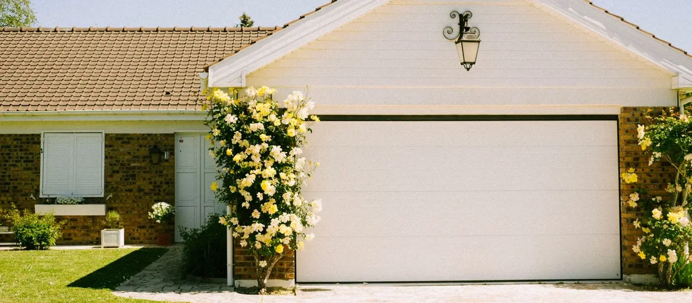 Brick and tile suburban home with a wide cream sectional garage door and driveway