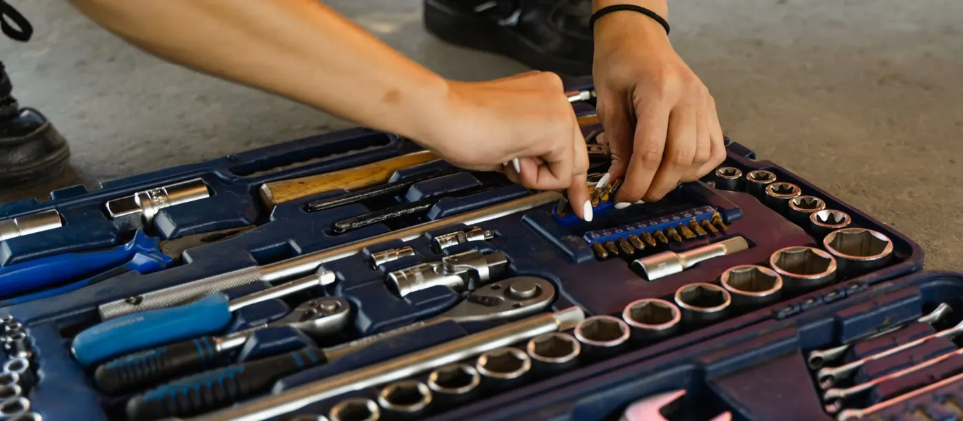 Hand lifting a socket from an open tool kit on a garage floor